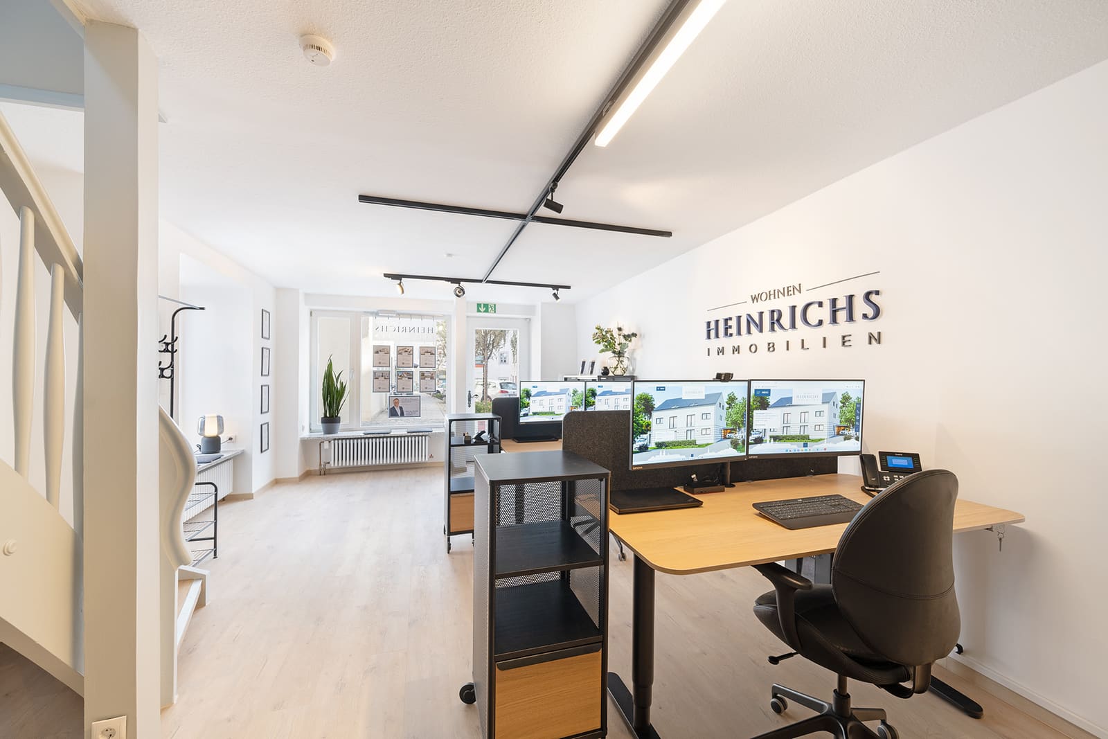 Moderne Arbeitsplätze im Büro von Heinrichs Immobilien mit Logo-Wand