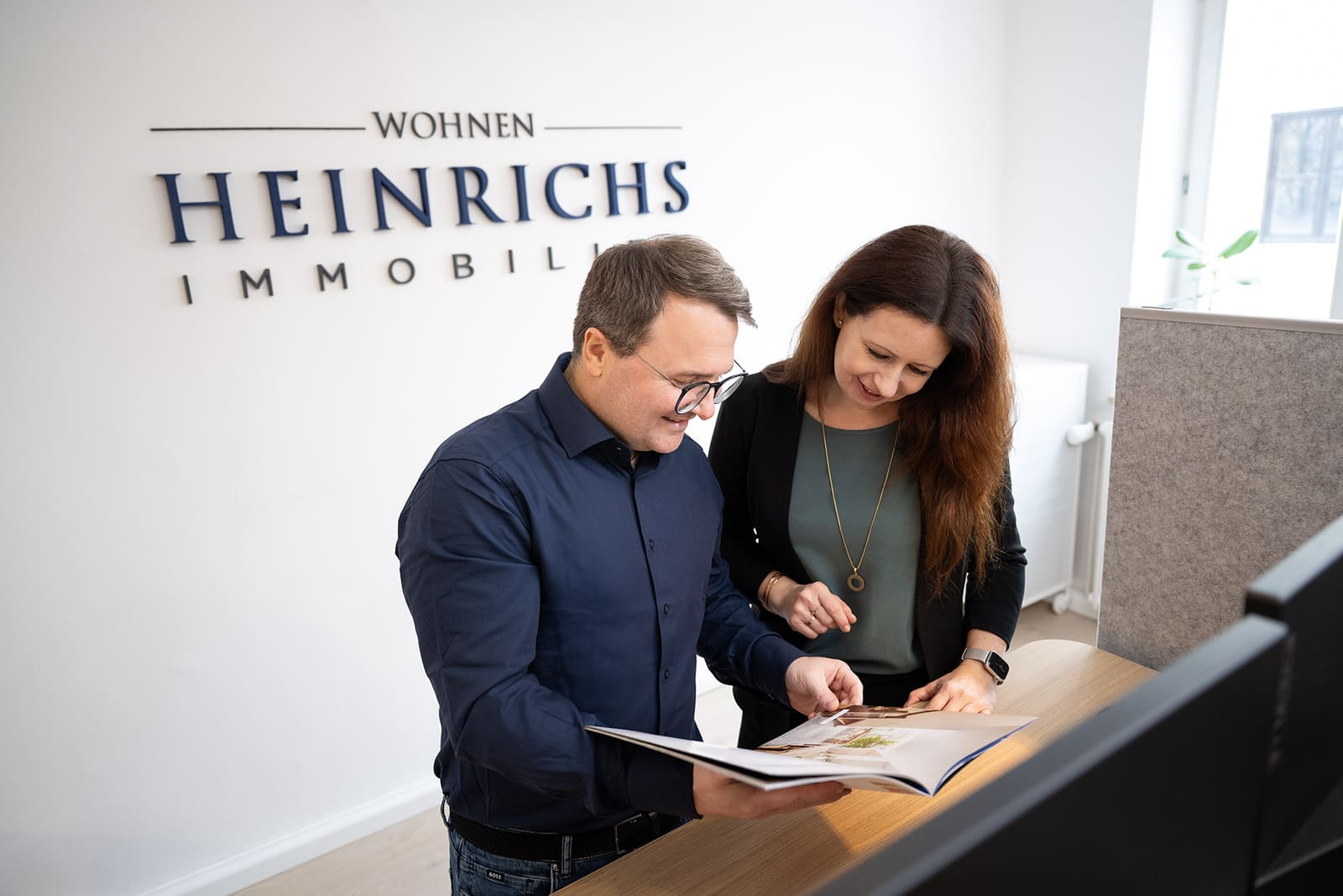 Andreas Heinrichs bespricht ein Exposé mit einer Mitarbeiterin im Ladenbüro