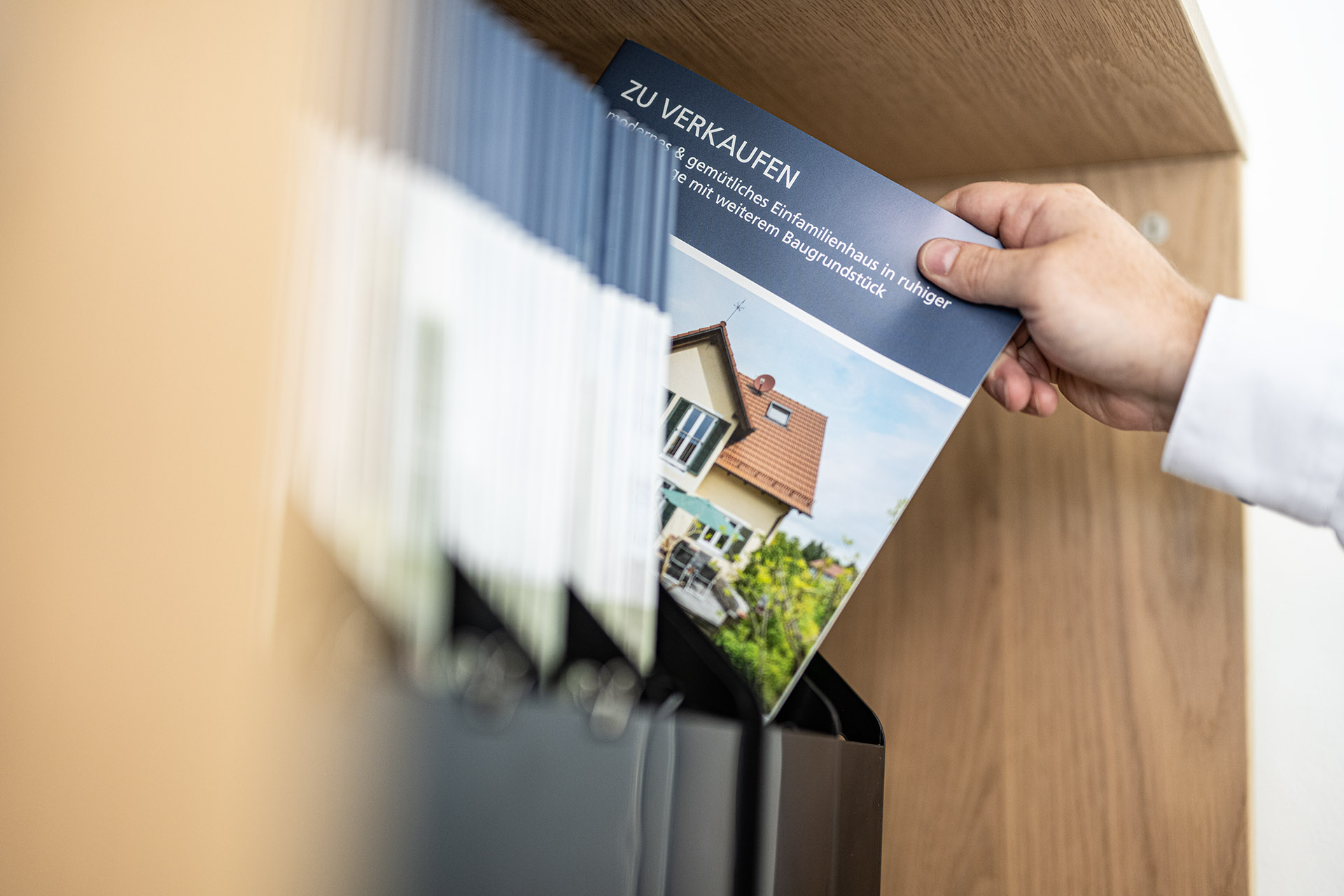 Gedruckte Verkaufs-Exposés im Regal des Büros von Heinrichs Immobilien